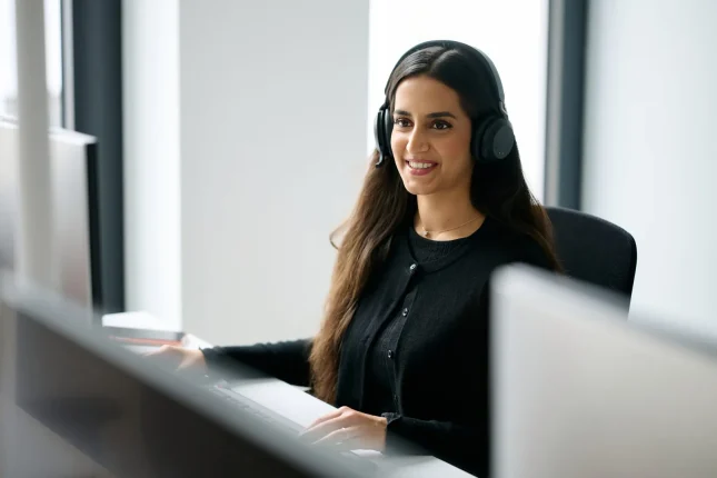 Junge Kollegin mit Headset an ihrem Arbeitsplatz
