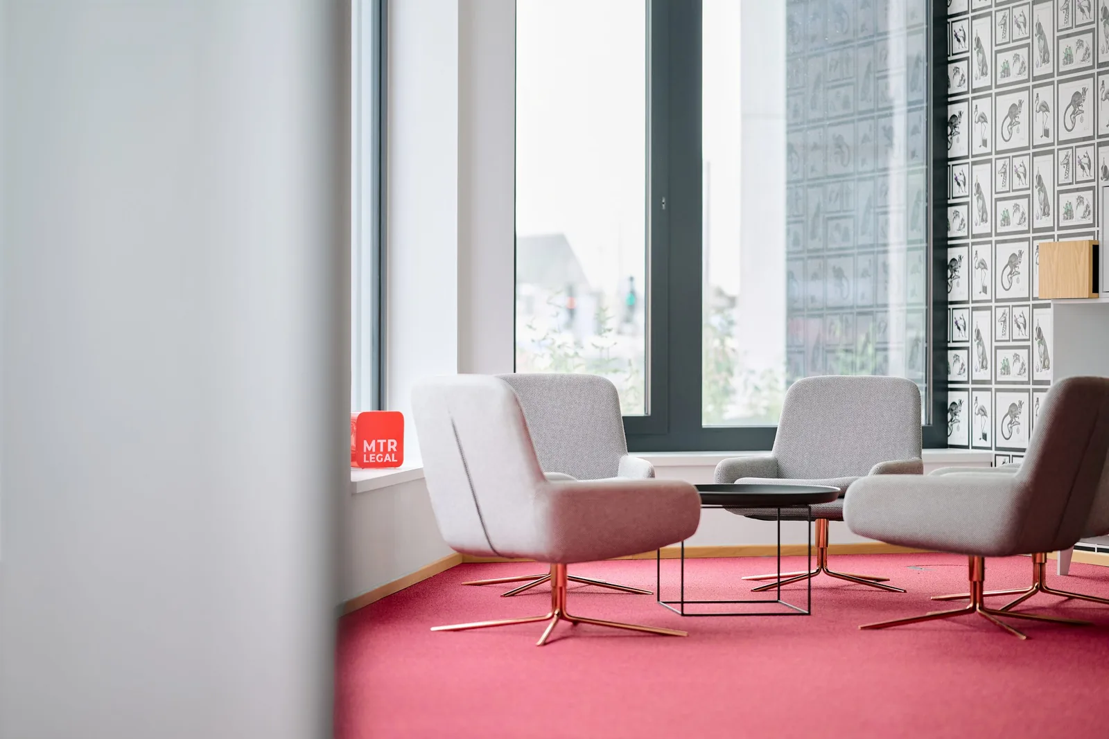 Lounge-Ecke im Kölner Büro von MTR Legal mit Sesseln und rotem Kanzleischild