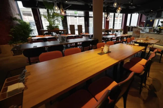 Restaurant im Haus mit Holztischen, roten Stühlen und Pendelleuchten