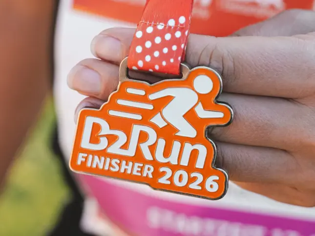 Hand hält eine Medaille mit der Aufschrift B2Run Finisher 2026