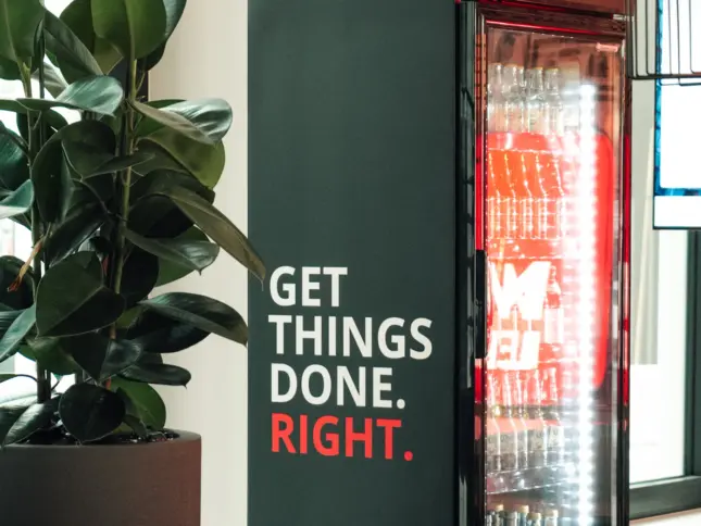 Getränkekühlschrank mit der Aufschrift GET THINGS DONE. RIGHT. neben einer Zimmerpflanze